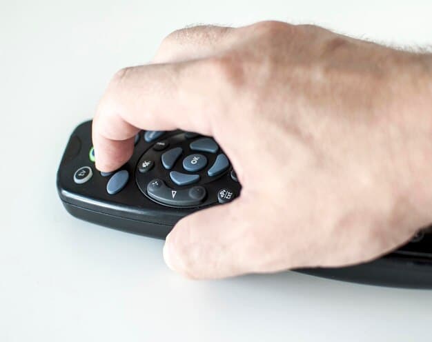 A close up shot of a remote control in a hand, poised to select a streaming service on a smart TV interface. The TV displays a variety of streaming apps, each with eye-catching visuals and logos, arranged in a grid format. Soft ambient light reflects off the TV screen, highlighting the hand and remote.