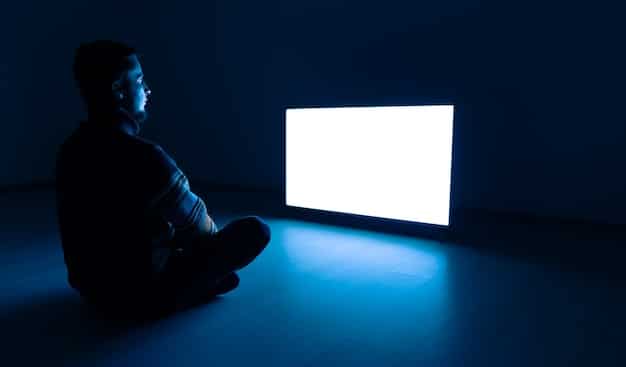 A person sitting on a couch, illuminated by the light of a television screen, holding a remote control and looking intently at the screen with a look of excitement and anticipation. The television displays several buttons representing different choices in the storyline, which the person can select using the remote control.