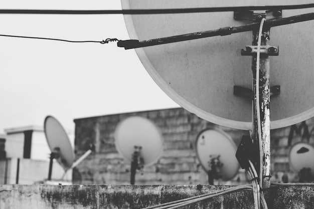 A historical photograph showcasing an early CATV antenna installation in a rural area of the United States. The antenna is large and prominently visible against a backdrop of mountains and sparsely populated houses, illustrating the early purpose of cable TV as a means of signal reception in remote locations.